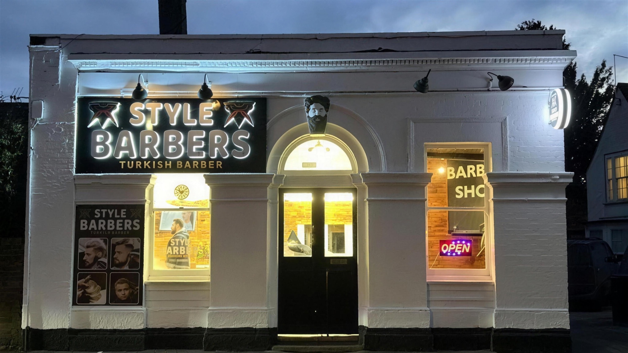 Style Barbers shopfront on London Road, Old Harlow, lit at dusk